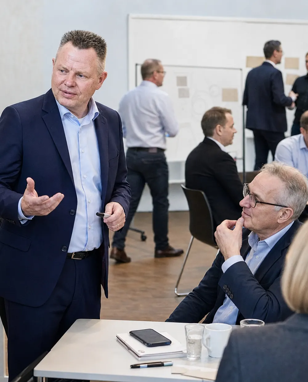 Deltagere i dialog under et virksomhedsforløb med whiteboards i baggrunden